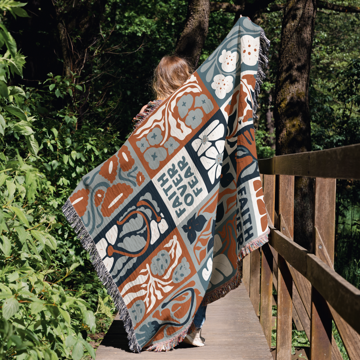 Person walking on a wooden bridge with a colorful patterned blanket draped over their shoulders.