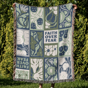Blanket with floral patterns and 'Faith Over Fear' text held by a person outdoors.