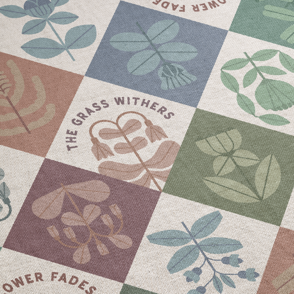 Patterned fabric with leaf designs and 'The Grass Withers' text on a checkered background.