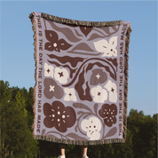 Floral patterned blanket with text against a blue sky and green trees background