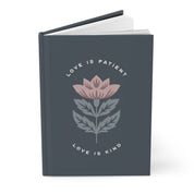 Notebook with floral design and text 'Love is Patient, Love is Kind' on a white background