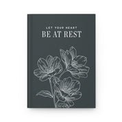 Book with floral design and text 'Let your heart be at rest' on a dark background