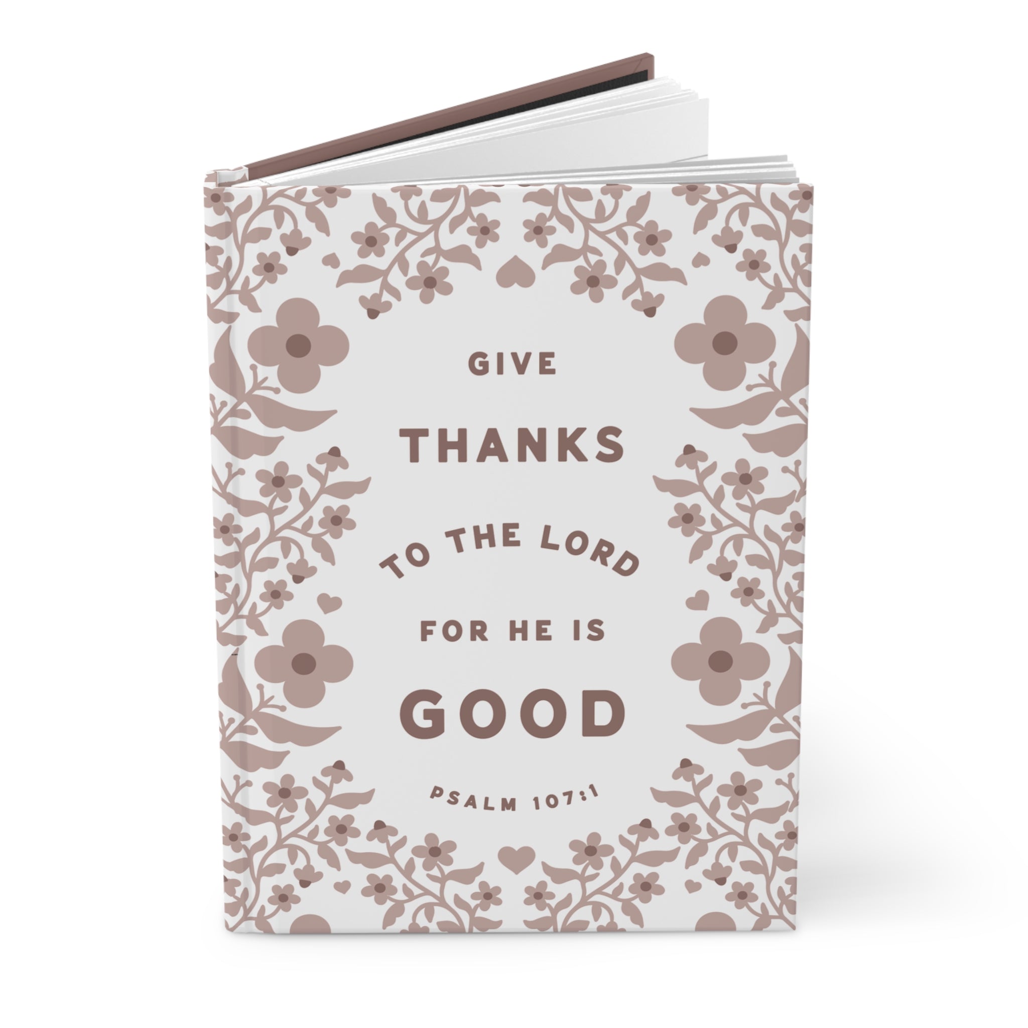 Notebook with floral design and text 'Give thanks to the Lord for he is good' on a white background