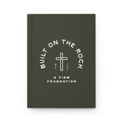 Dark gray notebook with white text and cross symbol on a white background