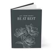 Book with floral design and text 'Let your heart be at rest' on a white background