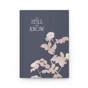 Notebook with floral design and text 'Be Still and Know' on a white background