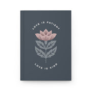 Notebook with floral design and text 'Love is Patient, Love is Kind' on a dark gray background