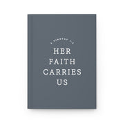 Gray notebook with 'Her Faith Carries Us' text on a white background