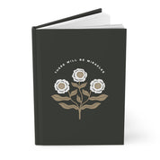 Black notebook with floral design and 'There Will Be Miracles' text on a white background