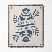 Blanket with floral design and text 'God is good all the time' on a white background