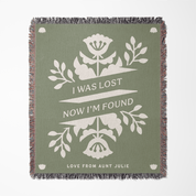 Green blanket with white floral design and text on a white background