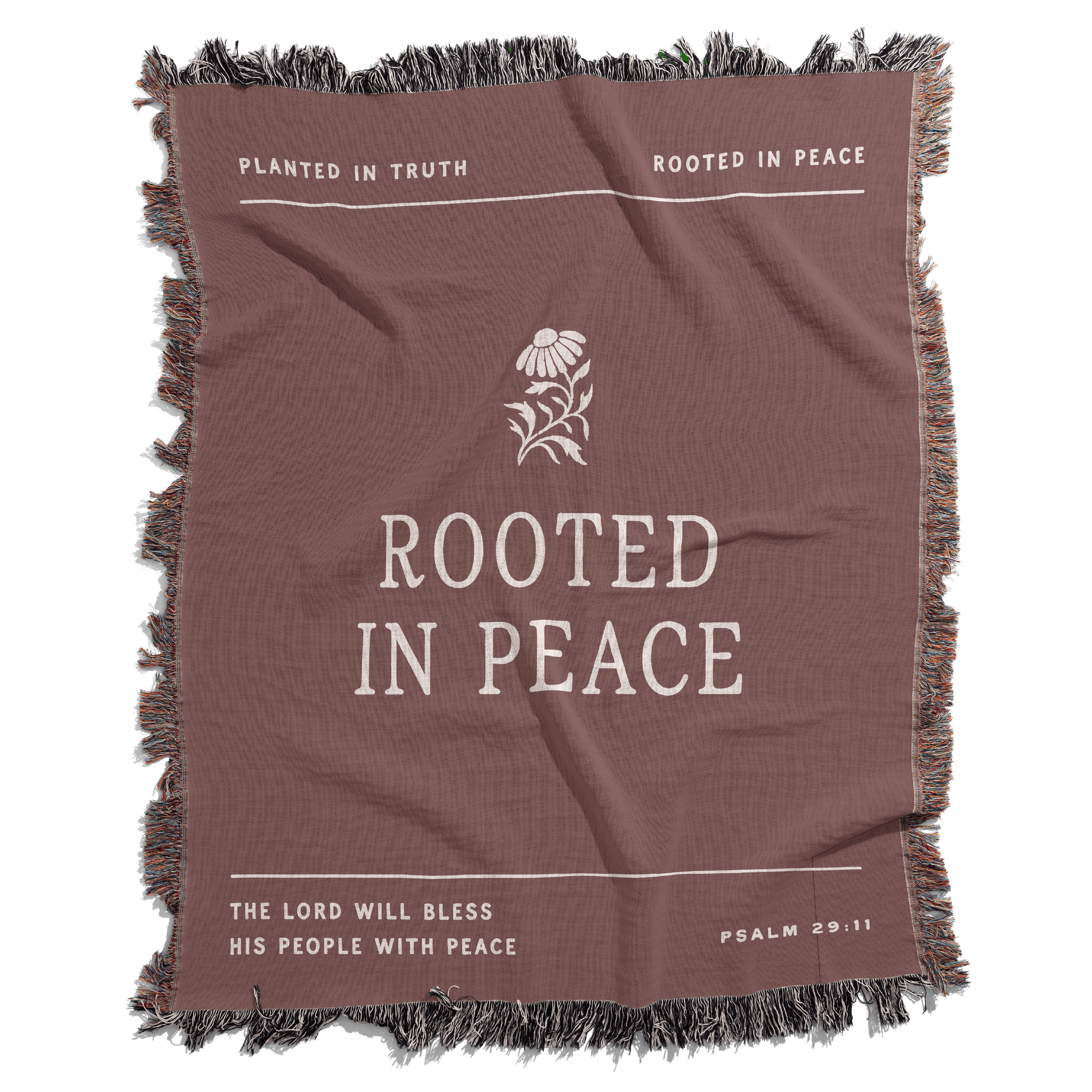 Brown blanket with 'Rooted in Peace' text and floral design on a white background