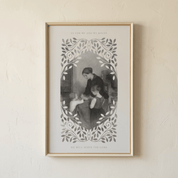 A framed art print featuring a vintage black and white illustration of a mother and child, surrounded by a decorative leafy border, hanging on a textured beige wall.
