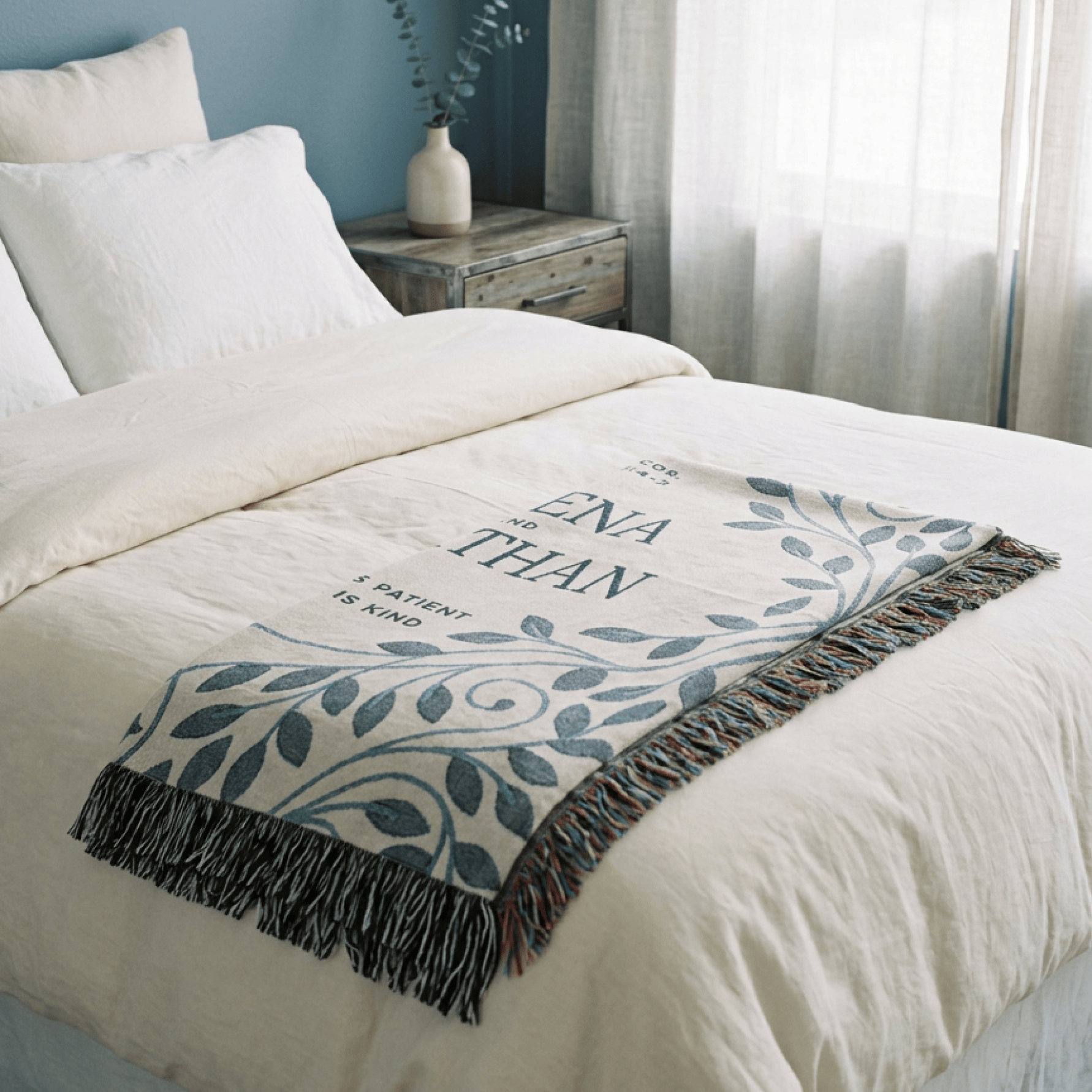 Decorative throw blanket with text and leaf pattern on a bed in a bedroom setting.