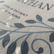 Textured fabric with leaf pattern and text 'LOVE IS PATIENT AND KIND' on a gray background