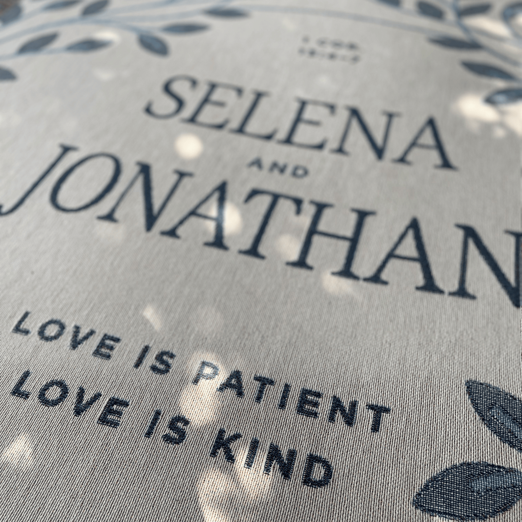 Text on a fabric with 'Selena and Jonathan' and 'Love is Patient, Love is Kind' printed on it.