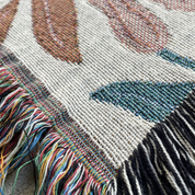 Close-up of a woven textile with colorful patterns and fringes.