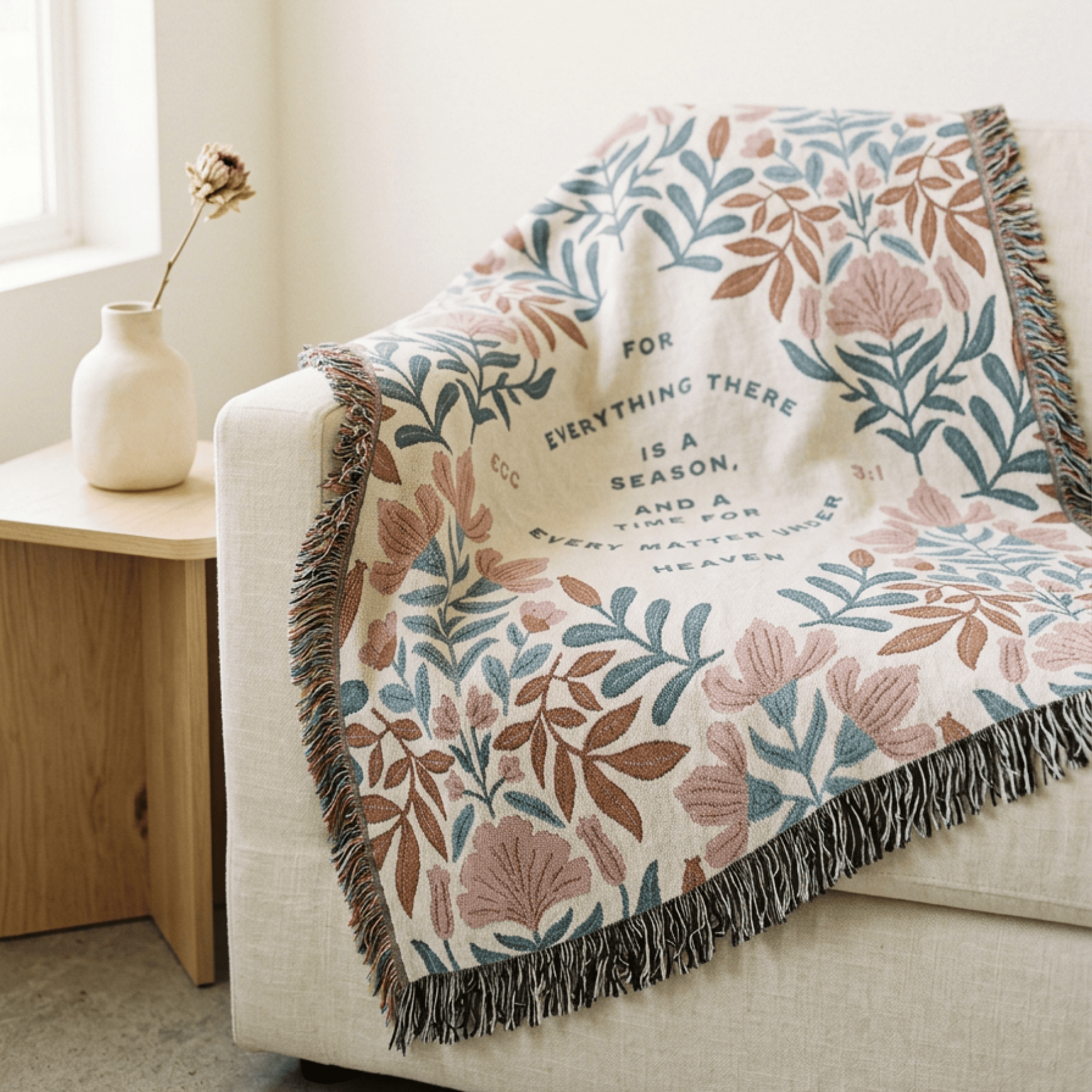 Floral patterned throw blanket with text draped over a sofa in a living room.