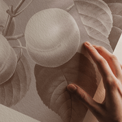 Hand holding a round object against a textured background with leaves