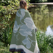 Person wearing a green floral-patterned shawl by a pond