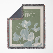 Woven blanket with floral design and text on a white background
