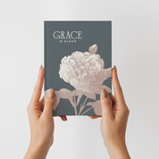Book titled 'Grace in Bloom' held by hands against a light gray background