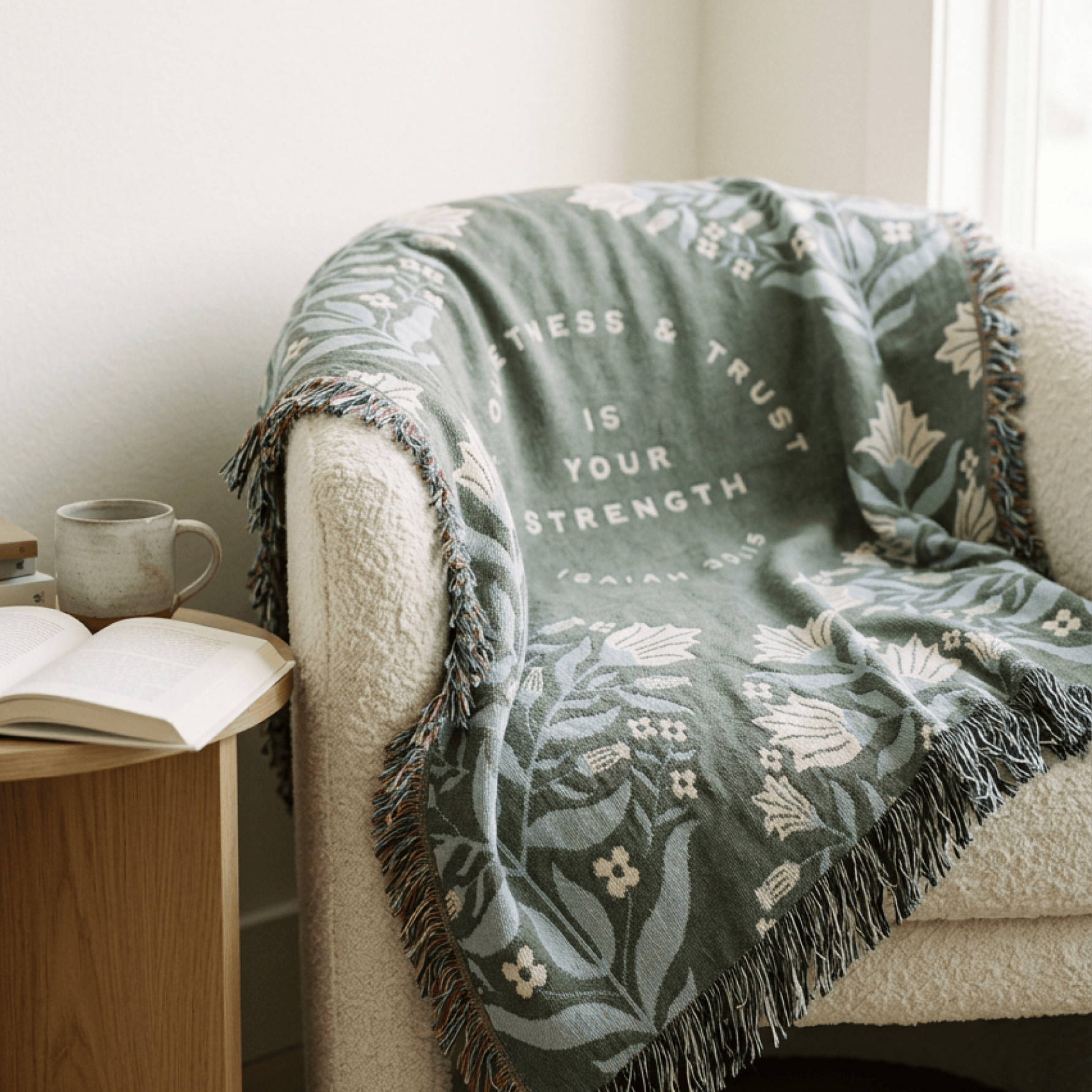 Christian woven blanket with Isaiah 30:15 botanical pattern draped over white armchair in living room