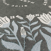 Close-up of In Quietness and Trust text woven into sage green blanket fabric
