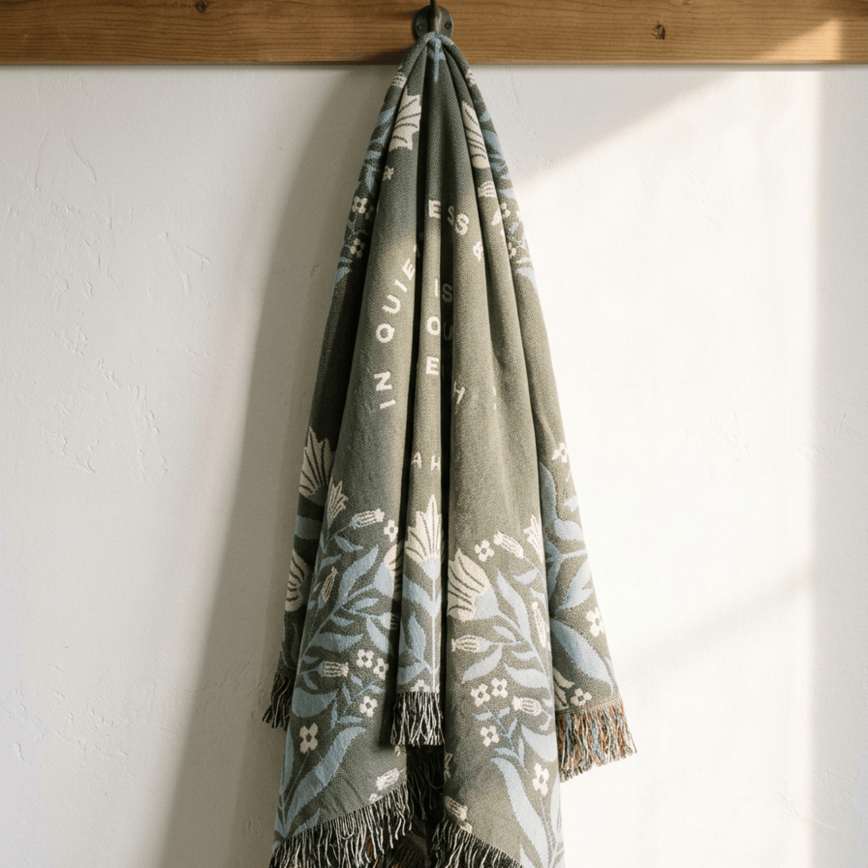 Christian woven blanket hanging vertically showing full length fringe and scripture text
