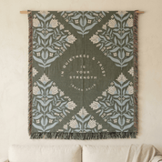 Sage green religious throw blanket draped over chair in natural light