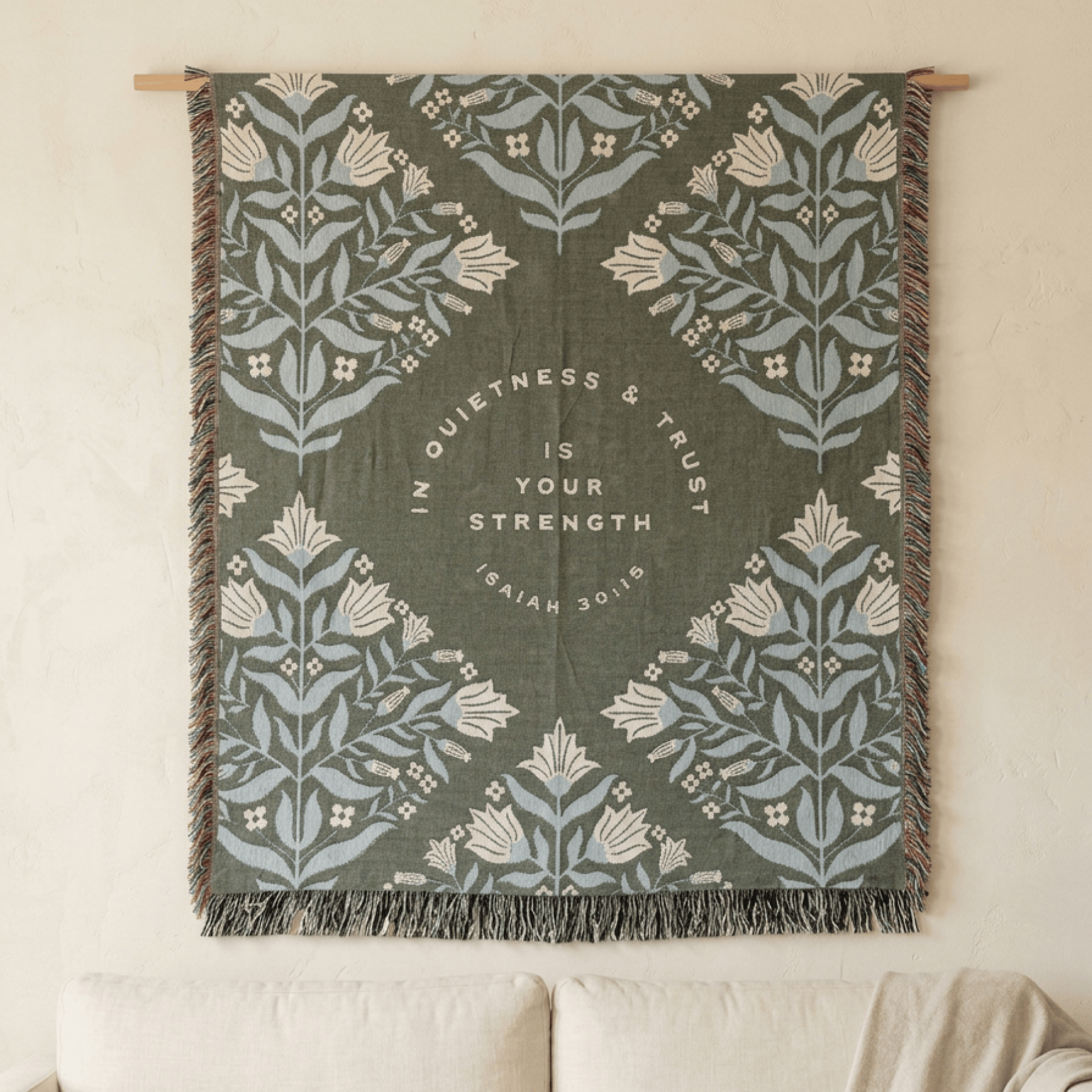 Sage green religious throw blanket draped over chair in natural light