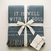 Blue blanket with 'It is well with my soul' text, tied with a white ribbon on a light background