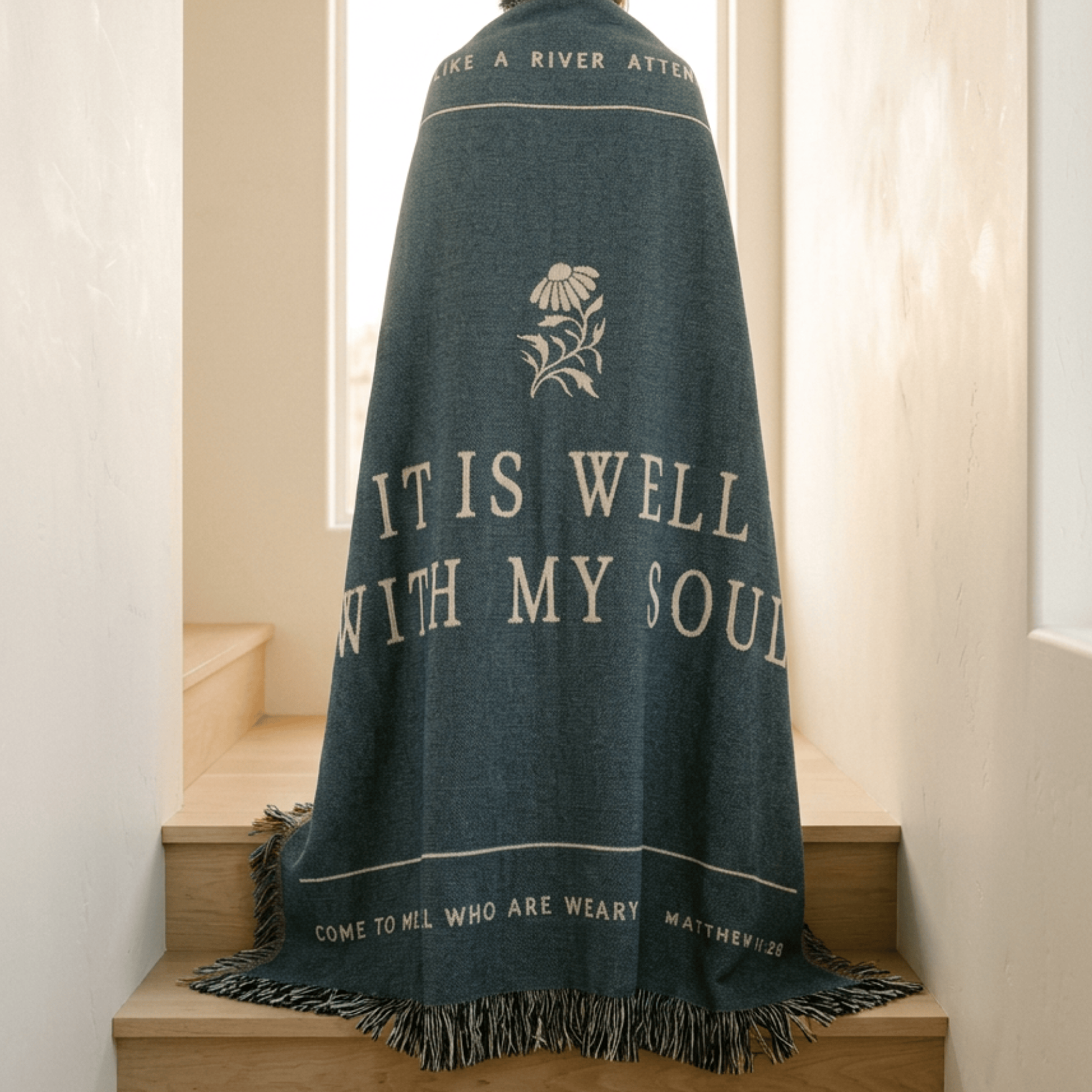 Blue prayer shawl with text and floral design draped over a wooden surface.