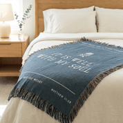 Blue throw blanket with text on a bed in a bedroom setting
