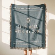 Blue throw blanket with text and floral design on a neutral background