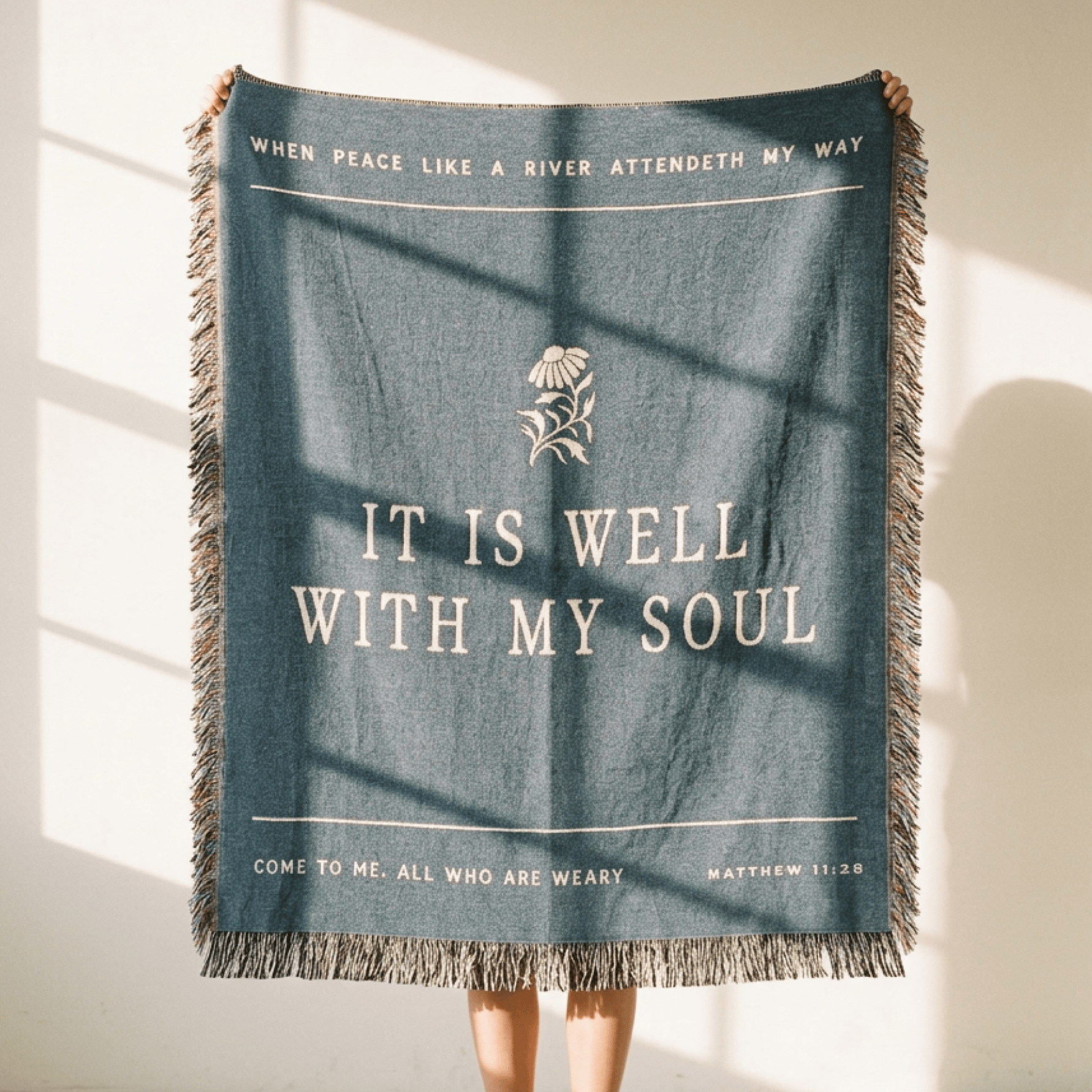 Blue throw blanket with text and floral design on a neutral background