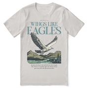 Christian t-shirt with the phrase “Wings Like Eagles” and an eagle illustration, inspired by Isaiah 40:31; unisex faith tee representing strength, renewal, and trust in God.