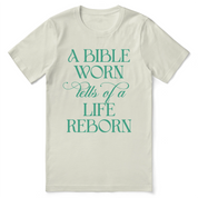Christian t-shirt with the phrase “A Bible Worn Tells of a Life Reborn”; unisex cotton tee celebrating transformation through God's Word.