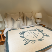 Bed with decorative blanket featuring text and pillows in a bedroom setting