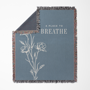 Gray blanket with floral design and 'A Place to Breathe' text on a white background