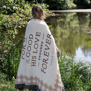 Person wrapped in a blanket with text by a pond