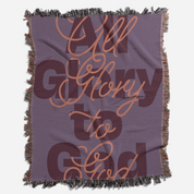 Blanket with 'All Glory to God' text in brown on a purple background