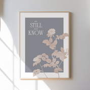 Framed artwork with floral design and text 'Be Still and Know' on a gray background