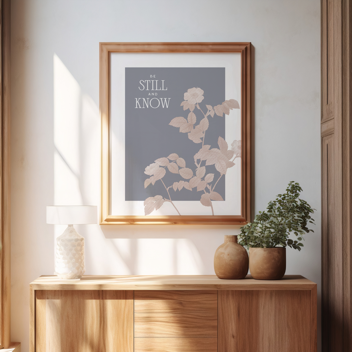 Framed artwork with floral design and text on a wall above a wooden console table.