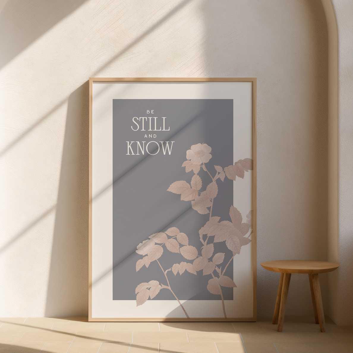 Framed artwork with floral design and motivational quote on a wall with a wooden stool.