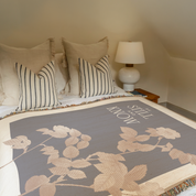 Bed with floral blanket and striped pillows, nightstand with lamp.