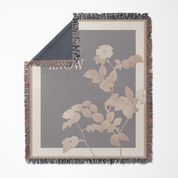 Floral-patterned woven blanket with fringe on a gray background