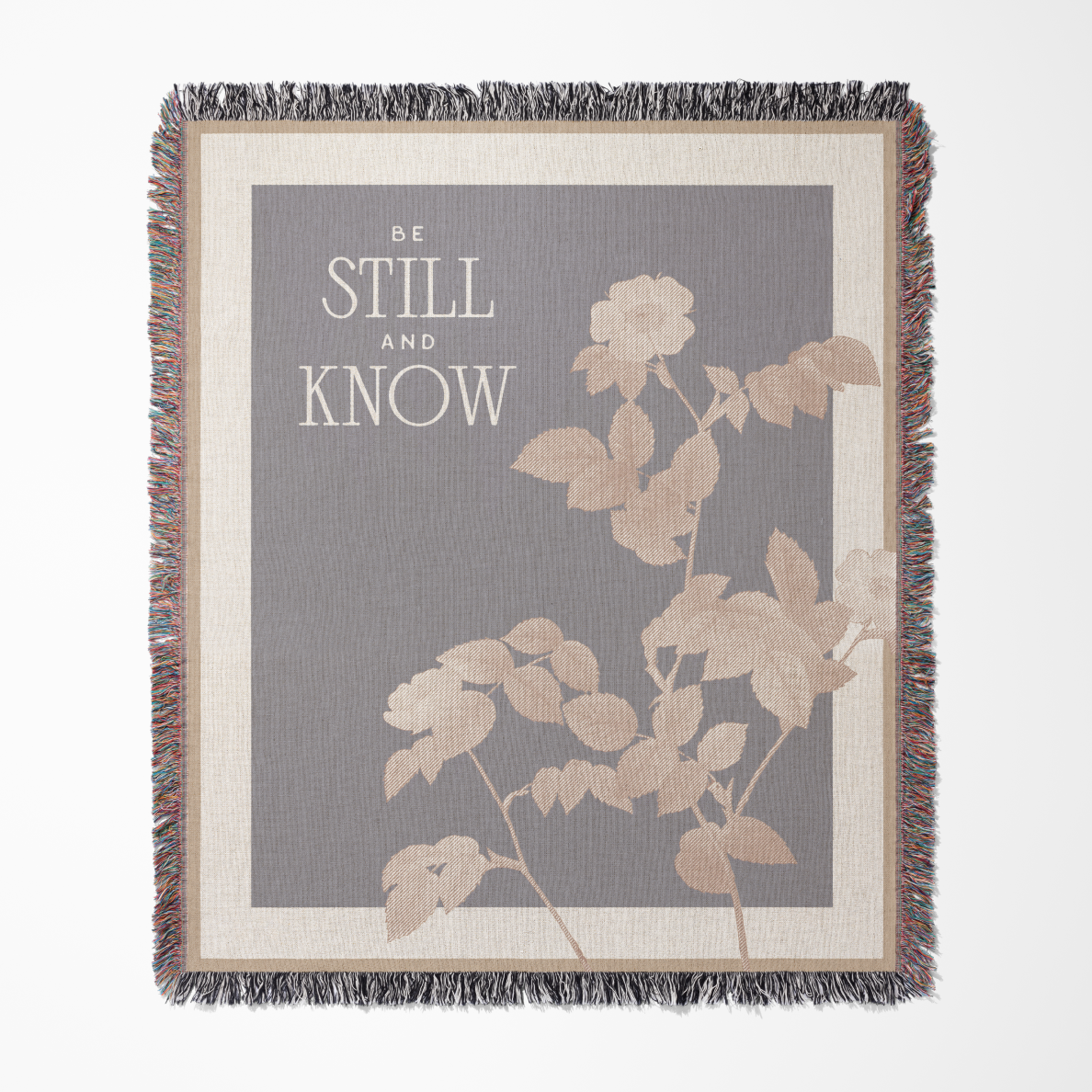 Blanket with floral design and text 'Be Still and Know' on a gray background