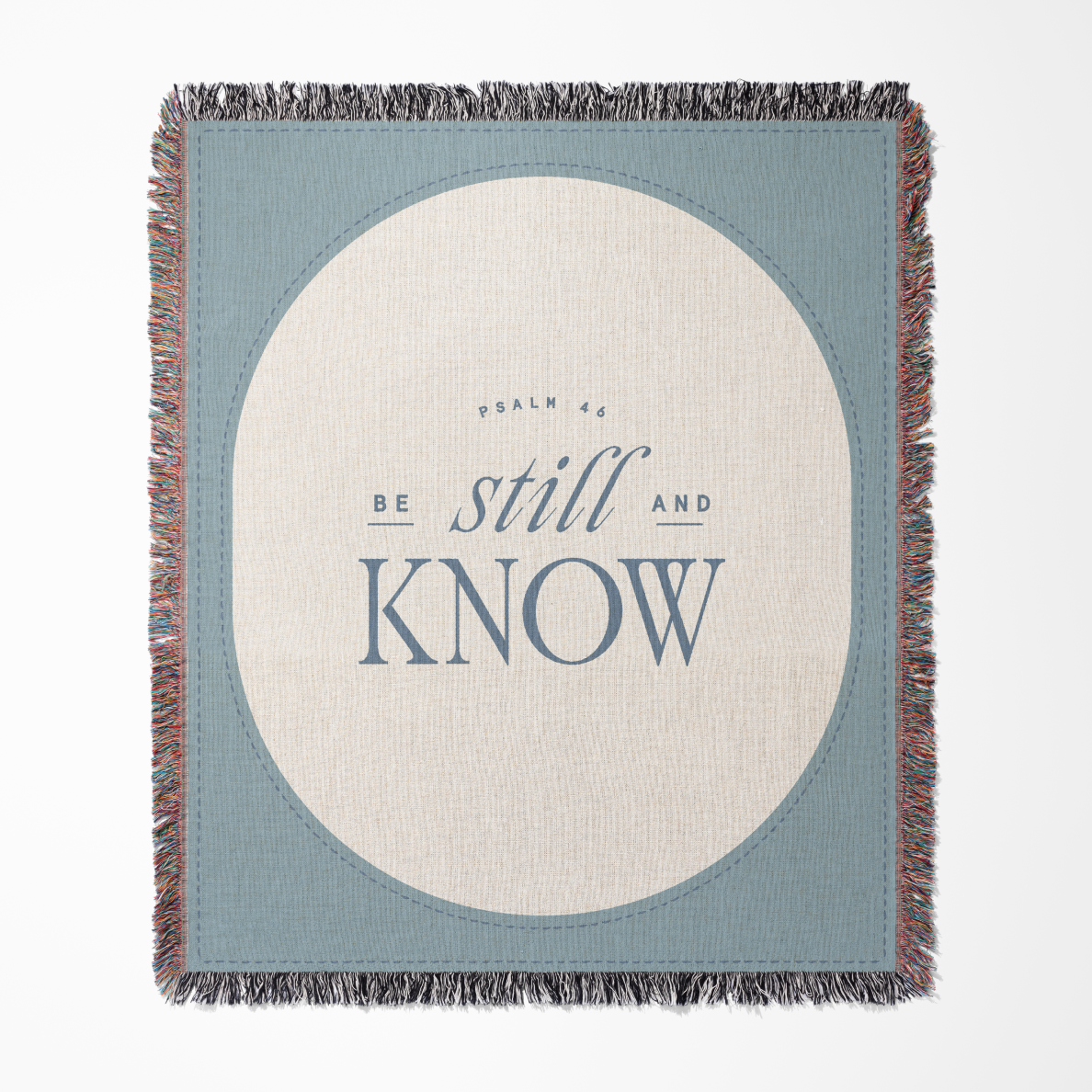 Blanket with 'Be still and know' text on a blue and beige background