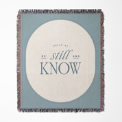 Blanket with 'Be still and know' text on a blue and beige background